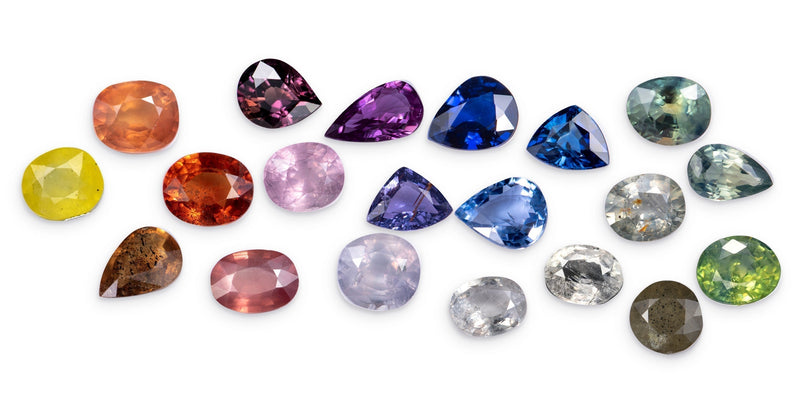 Loose faceted sapphires in blue, pink, purple, orange, yellow, green, grey and colorless, showing the range of sapphire colors
