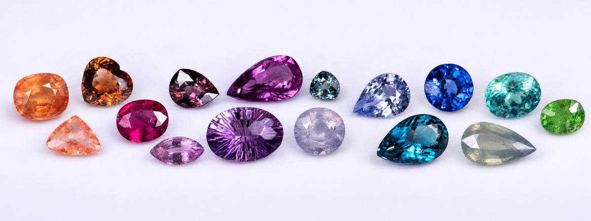Loose natural faceted gemstones in orange, pink, purple, blue and green, including pear, oval, heart and cushion cuts